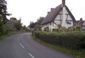 Narrow winding lane and pretty thatched cottage Longparish